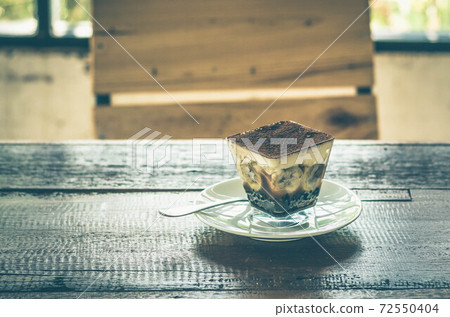 Banoffee pie on wooden table with blurred chair behind. 72550404