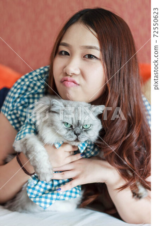 Close up of young Asian woman playing with her persian cat, human-animal relationships. Close up of young Asian woman playing with her persian cat, human-animal relationships. 72550623