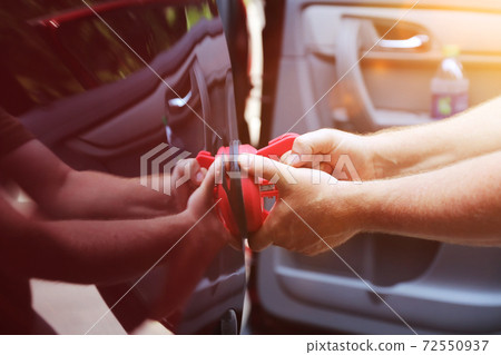 Man fixing car dent by himself Man fixing car dent by himself 72550937