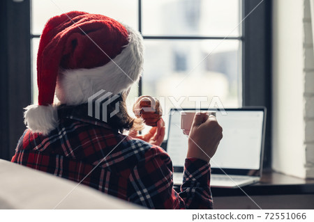 Back view of lonely european young woman wrapped in a plaid with with alarm clock sitting near window at cold winter day. Back view of lonely european young woman wrapped in a plaid with with alarm clock sitting near window at cold winter day. 72551066