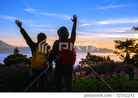 asian couples Tourists with backpacks Standing watching landscape view on the mountain,Beautiful landscape And the light of the beautiful sun on the Sky asian couples Tourists with backpacks Standing watching landscape view on the mountain,Beautiful landscape And the light of the beautiful sun on the Sky 72552243