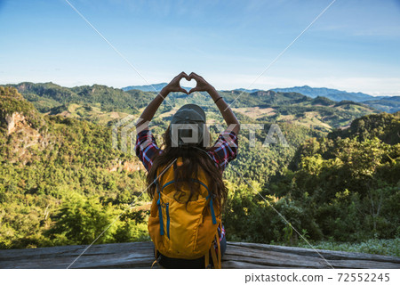 Young woman Tourists with backpacks Happy to travel She raised her hand to make a heart shape and enjoy the natural scenery on the mountain. 72552245