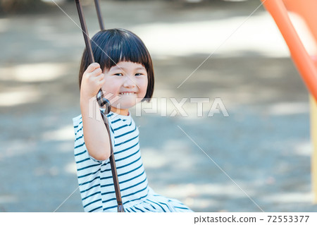 A girl playing with a swing 72553377