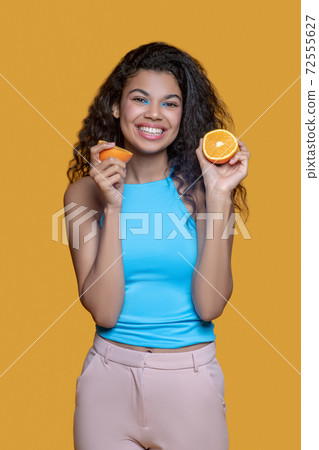 Young dark-haired smiling woman with orange in hands 72555627