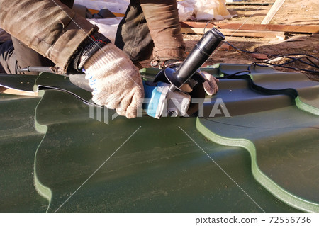 The master cuts a professional metal sheet for installation on the roof of the house 72556736