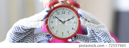 Builder holds red alarm clock in his hands. Builder holds red alarm clock in his hands. 72557985