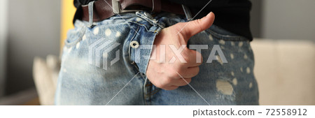 Male hand sticking out of fly of his jeans and showing thumb up close-up Male hand sticking out of fly of his jeans and showing thumb up close-up 72558912