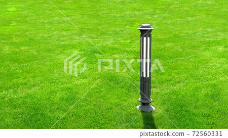 Iron outdoor garden lighting lantern on a green meadow lawn with grass with copy space for text on sunny summer day. Iron outdoor garden lighting lantern on a green meadow lawn with grass with copy space for text on sunny summer day. 72560331