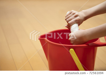 一個水桶，一個女人的手在房間裡擠一塊碎布 72561094