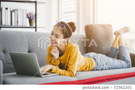 Beautiful young asian woman lying down and using computer laptop 72562201