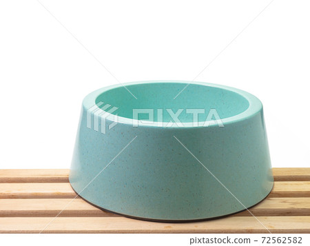 The close up of empty blue green plastic dog bowl, pet equipment with wood plank on white background. 72562582