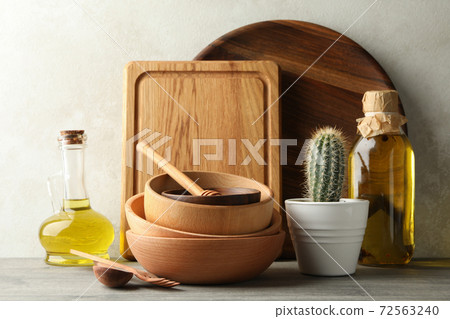 Different wooden kitchenware, oil and cactus on gray table Different wooden kitchenware, oil and cactus on gray table 72563240