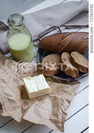 Sliced bread with a milk and butter on a on natural wooden board. Rustic style. Sliced bread with a milk and butter on a on natural wooden board. Rustic style. 72563430
