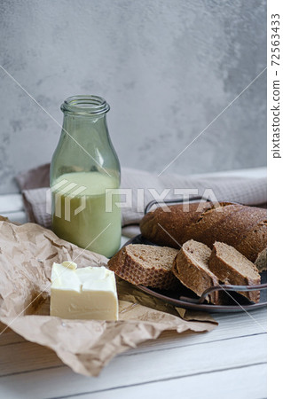 Sliced bread with a milk and butter on a on natural wooden board. Rustic style. Sliced bread with a milk and butter on a on natural wooden board. Rustic style. 72563433