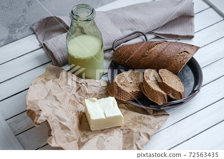 Sliced bread with a milk and butter on a on natural wooden board. Rustic style. Sliced bread with a milk and butter on a on natural wooden board. Rustic style. 72563435