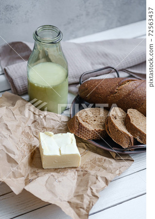 Sliced bread with a milk and butter on a on natural wooden board. Rustic style. Sliced bread with a milk and butter on a on natural wooden board. Rustic style. 72563437