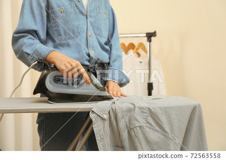 Woman in jeans ironing shirt with iron Woman in jeans ironing shirt with iron 72563558