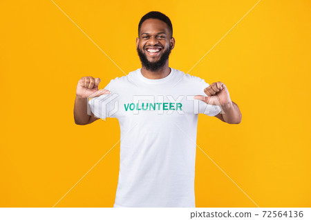 Volunteer guy pointing fingers at himself posing on yellow background 72564136