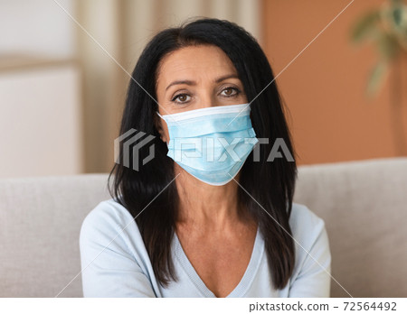 Portrait of mature woman wearing disposable mask to prevent infection 72564492