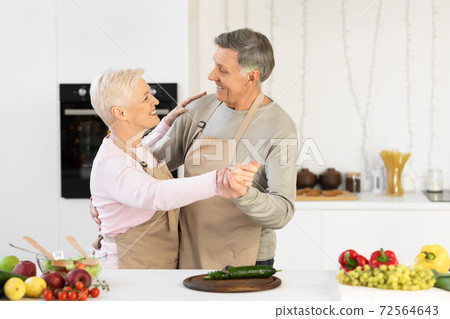 Cheerful Elderly Couple Dancing In Kitchen Having Fun At Home 72564643