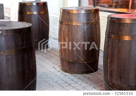 brown wooden rum barrel on the street on stone paving slabs, bar restaurant decorations close up nobody. brown wooden rum barrel on the street on stone paving slabs, bar restaurant decorations close up nobody. 72565310