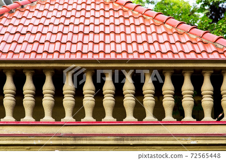 balustrade with stone pillars of a balcony in the background a roof of red ceramic tiles. 72565448