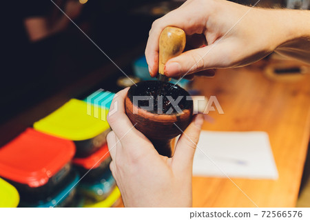 Preparing hookah for smoking, filling clay bowl with tobacco, male hands visible. Preparing hookah for smoking, filling clay bowl with tobacco, male hands visible. 72566576