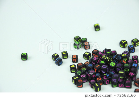 Colorful alphabet printed on small black plastic cubes and placed randomly on white background.  72568160