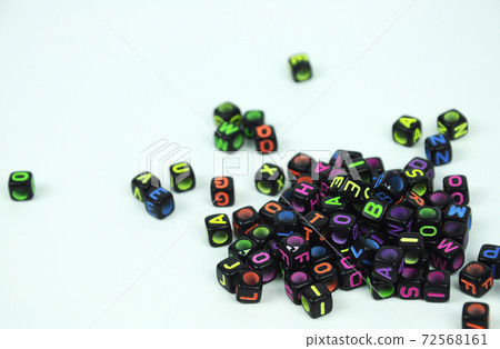 Colorful alphabet printed on small black plastic cubes and placed randomly on white background. Colorful alphabet printed on small black plastic cubes and placed randomly on white background. 72568161