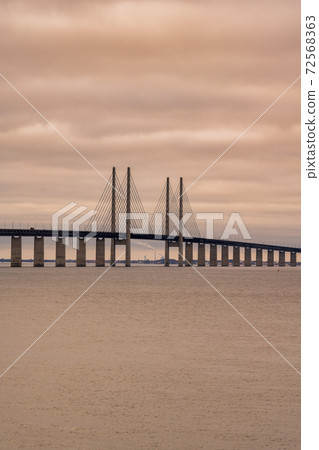 The Oresund Bridge, the bridge and underwater tunnel connecting Malmo, Sweden with Copenhagen, Denmark. A beautiful sunset sky in the background 72568363