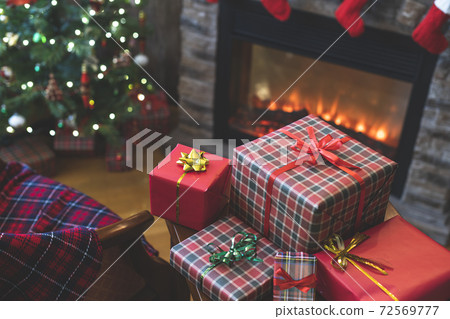 Woman putting american dollars in red christmas sock sitting near christmas tree and fireplace and packing gift box. Woman putting american dollars in red christmas sock sitting near christmas tree and fireplace and packing gift box. 72569777