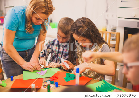 Mother creates paper greeting cards together with her chldren Mother creates paper greeting cards together with her chldren 72570970