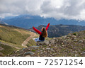 Young woman is sitting on the cliff of the mountain in Sochi, Russia. 72571254