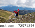Young woman is sitting on the cliff of the mountain in Sochi, Russia. 72571256