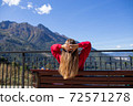Young woman is sitting on bench in Sochi with mountain view on the background, Russia. 72571278