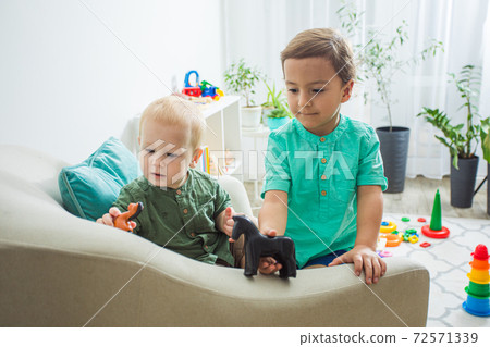 Boys playing horse ride on armchair back Boys playing horse ride on armchair back 72571339
