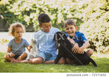 The children like to play with pets outdoors The children like to play with pets outdoors 72571692