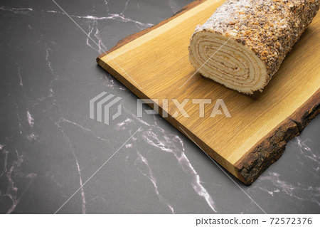 pastry roll on a wooden Board on black marble 72572376