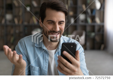 Smiling man talk on video call on smartphone 72572750