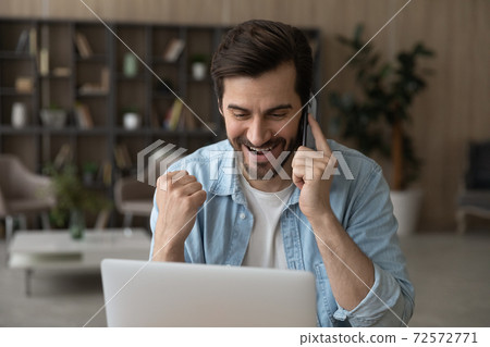 Overjoyed man talk on cell celebrate online win 72572771