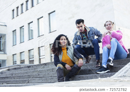 cute group of teenages at the building of university with books huggings, diversity nations real students lifestyle 72572782