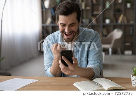 Overjoyed man triumph winning lottery on cellphone 72572783