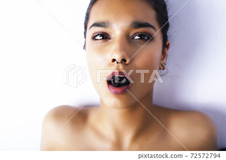 young pretty indian woman with dry fruit in mouth on white background 72572794