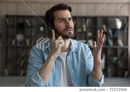 Unhappy man feel distressed talking on smartphone Unhappy man feel distressed talking on smartphone 72572948