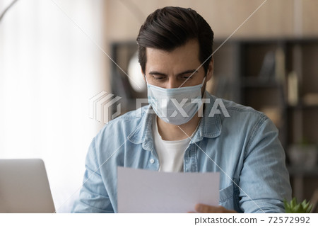 Male employee in facemask work with documents 72572992