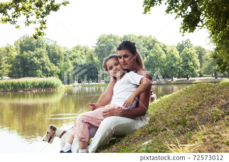 young pretty caucasian mother walking with little cute daughter and dog fox terrier, lifestyle people concept young pretty caucasian mother walking with little cute daughter and dog fox terrier, lifestyle people concept 72573012