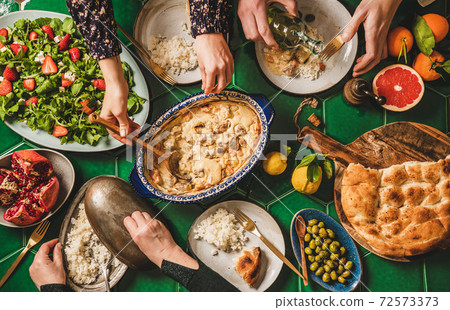 People eating Turkish dinner with lamb over green People eating Turkish dinner with lamb over green 72573373