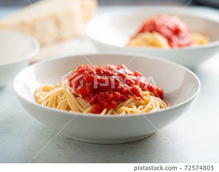 Spaghetti with tomato sauce and basil on a plate 72574803
