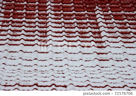 Red tiles and white snow on the roof 72576706