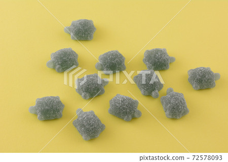 Sour green gummy candy in shape of turtle on yellow background Sour green gummy candy in shape of turtle on yellow background 72578093